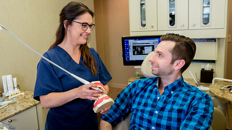 Staff showing patient procedure using model of teeth.
