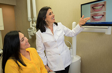 Doctor Alidadi showing patient photos on screen of teeth before and after a treatment.