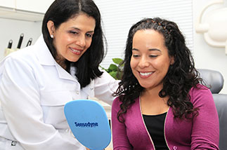 Patient looking at her beautiful new smile in a handheld mirror.